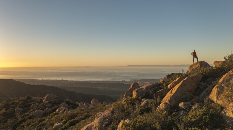 Hiker on rock overlooking the Pacific ocean