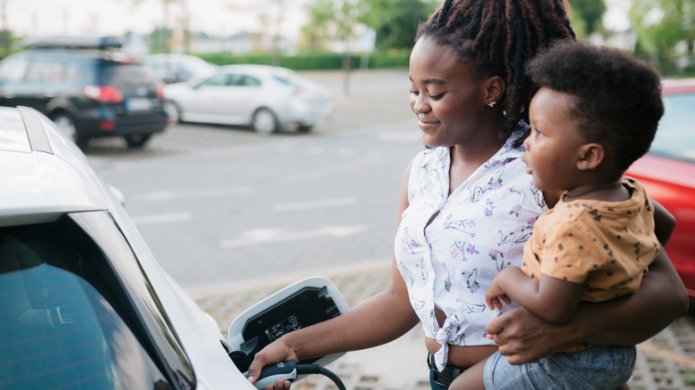 mother holding baby while pumping gas